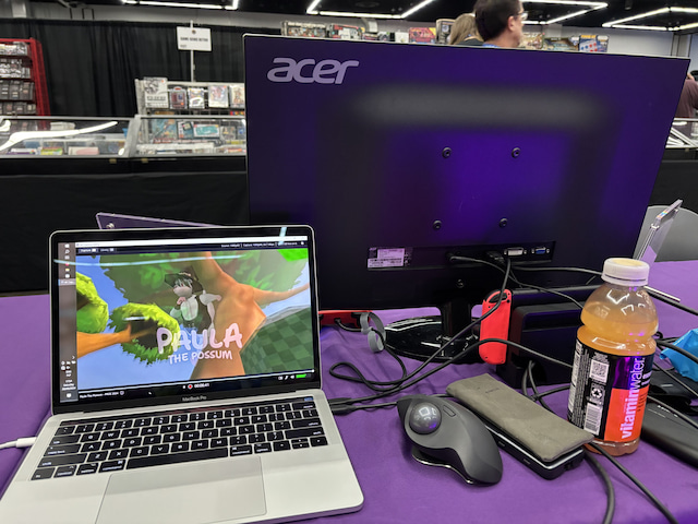 This was my view at the expo. My MacBook is in the bottom left corner and the Elgato Capture app is open. You can also see my MX Ergo mouse and a vitamin water that helped me stay hydrated throughout the day. You can also see the Switch in the Dock and the Elgato HD60 capture card.